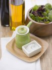 Вид крупным планом соли с небольшим зеленым кувшином, маслом, уксусом и салатом из листьев — стоковое фото