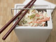 Coleslaw cabbage salad in white container with chopsticks — Stock Photo