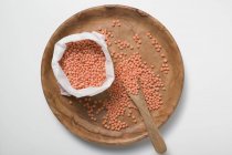 Vista dall'alto di lenticchie rosse su piatto di legno e in borsa — Foto stock
