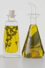 Vista de cerca de dos aceites de hierbas diferentes en botellas con hierbas - foto de stock