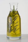 Крупный план розмаринового масла в графине с травой — стоковое фото