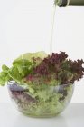 Öl auf Salatblätter gießen — Stockfoto