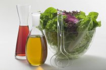 Closeup view of oil and vinegar in carafes beside salad bowl — Stock Photo