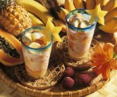 Vista de cerca de ensalada de frutas exóticas con leche de coco en dos vasos - foto de stock