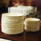 Closeup view of two piles of plates on wooden surface — Stock Photo