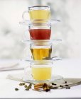 Vue rapprochée de quatre tasses et soucoupes en verre empilées avec différents thés — Photo de stock