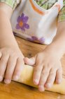 Closeup view of child forming dough to a roll — Stock Photo