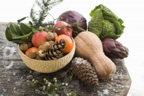 Vue rapprochée des pommes, légumes, noix et cônes sur table en bois — Photo de stock