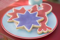 Nahaufnahme von verschiedenen Keksen mit rotem und blauem Zuckerguss auf dem Teller — Stockfoto