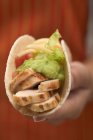 Closeup view of hand holding Taco filled with chicken and guacamole — Stock Photo