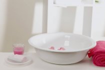 Bol à laver avec fleurs, savon, serviettes et bougie en verre — Photo de stock
