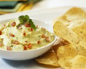Guacamole mit Chips auf weißem Teller über Tablett — Stockfoto