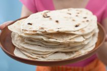 Closeup view of woman holding freshly baked tortillas on tray — Stock Photo