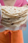 Closeup view of woman holding freshly baked tortillas on tea towel — Stock Photo