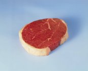 Beefsteak on blue background — Stock Photo