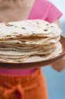 Nahaufnahme einer Frau mit frisch gebackenen Tortillas auf Tablett — Stockfoto