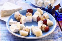 Käse und Trauben auf Stöcken — Stockfoto