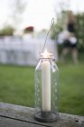 Daytime closeup view of lit candle in windlight on garden table — Stock Photo