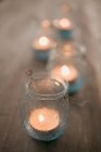Крупный план зажженных свечей в ветровом свете на деревянном столе — стоковое фото
