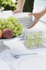 Closeup cropped view of person putting plates on table with fruit — Stock Photo