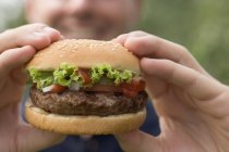 Primer plano vista de hombre sosteniendo hamburguesa grande - foto de stock