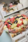 Cropped view of person holding fruit salad in plastic bowl — Stock Photo