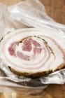 Closeup view of a slice of Pancetta on plastic food wrap — Stock Photo