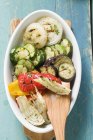Вид сверху на жареные овощи с деревянной лопаткой в овальной тарелке — стоковое фото