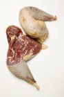 Closeup top view of two raw guinea-fowl legs on white surface — Stock Photo