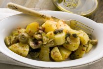 Pommes de terre frites épicées aux olives et câpres dans un plat de service — Photo de stock