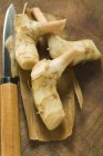 Vista ravvicinata delle radici e del coltello Galanga freschi sulla superficie di legno — Foto stock