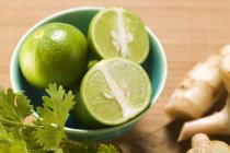 Limes in bowl with coriander — Stock Photo