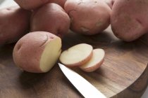 Цельный и нарезанный красный картофель — стоковое фото