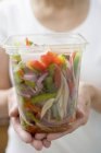 Mulher segurando recipiente de plástico de legumes, midsection — Fotografia de Stock