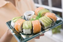Femme tenant maki sushi — Photo de stock