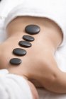 Liegende Frau bei Tränensteintherapie mit Reihe schwarzer Steine auf dem Rücken — Stockfoto