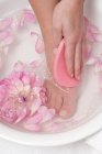 Підвищений обрізаний вид жінки миє ногу з рожевою губкою — стокове фото