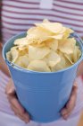 Woman holding potato crisps in blue bucket — Stock Photo