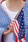 Vista ritagliata della donna che tiene bandiera americana — Foto stock