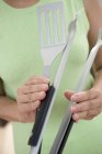 Woman holding barbecue tongs and spatula — Stock Photo
