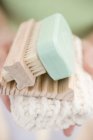 Mulher segurando sabão, saboneteira, escova e toalha — Fotografia de Stock