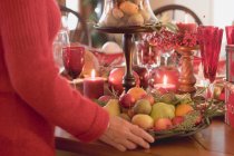 Frau stellt Schale mit Früchten auf den Tisch — Stockfoto