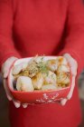 Woman holding dish of roasted onions, midsection — Stock Photo