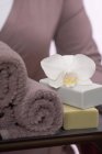 Donna che tiene asciugamani, saponi e orchidee su vassoio — Foto stock