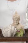 Donna che tiene statua di Buddha, candela e orchidea sul vassoio — Foto stock