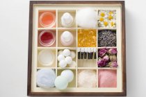 Various beauty products and flowers in type case — Stock Photo