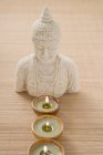 Tealights in front of Buddha statue — Stock Photo