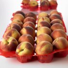 Peaches in red plastic — Stock Photo