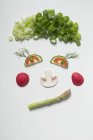 Cara divertida hecha de verduras, eneldo y setas en la superficie blanca - foto de stock