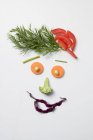 Amusing face made from vegetables and dill over white surface — Stock Photo